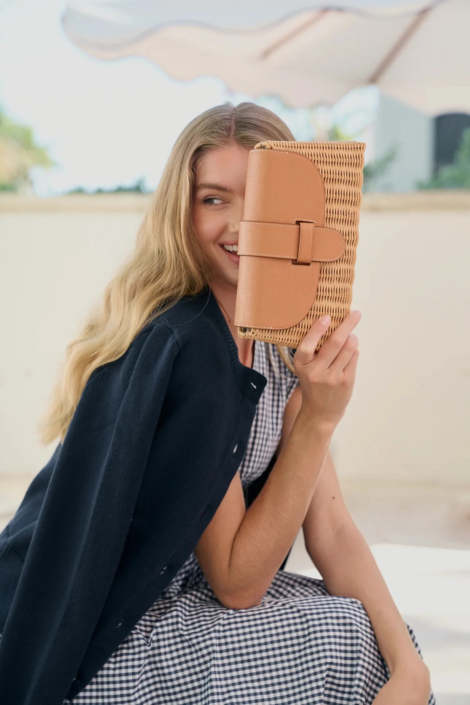 Woman holding a woven clutch under an umbrella