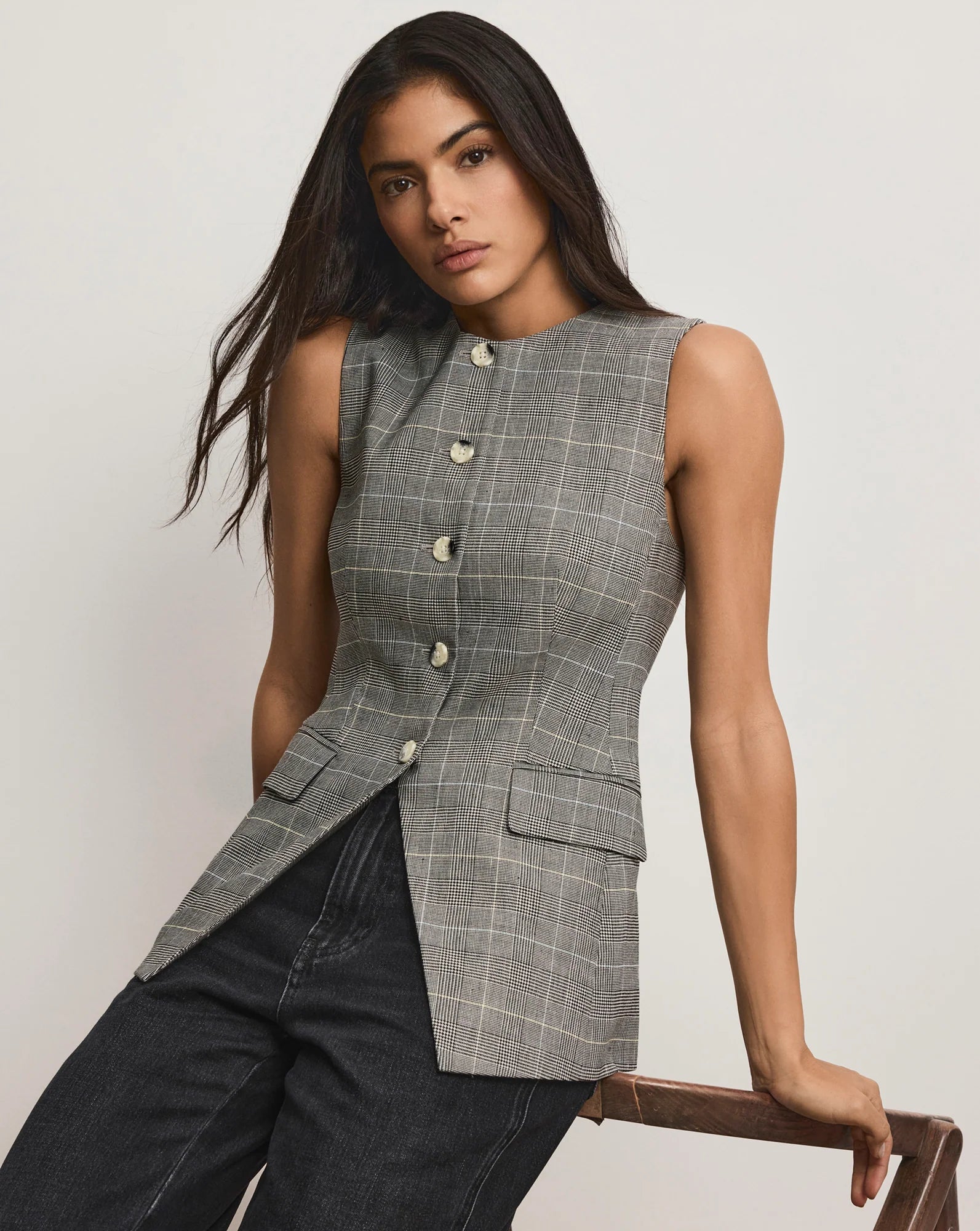 A woman wearing a grey vest and black denim jeans