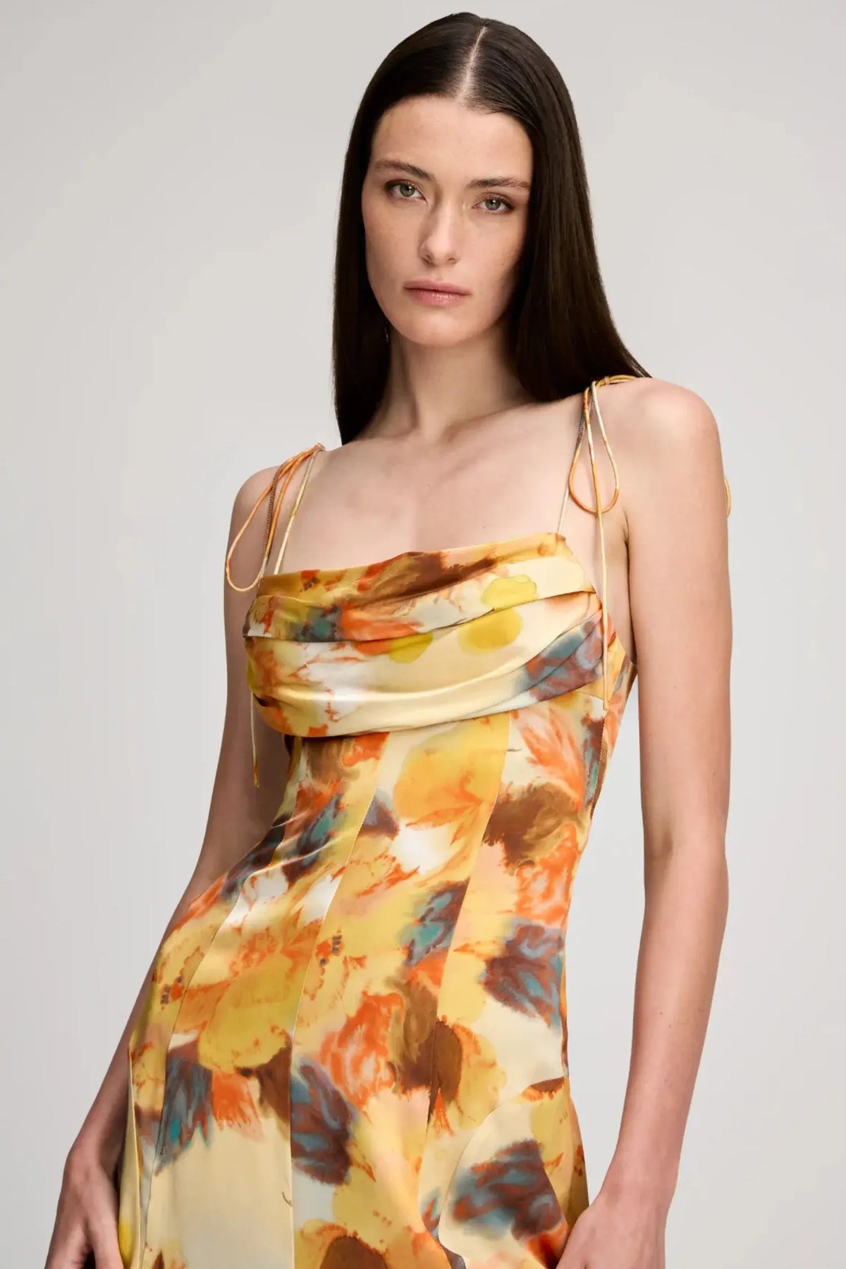 Woman wearing a colorful floral dress on a plain background