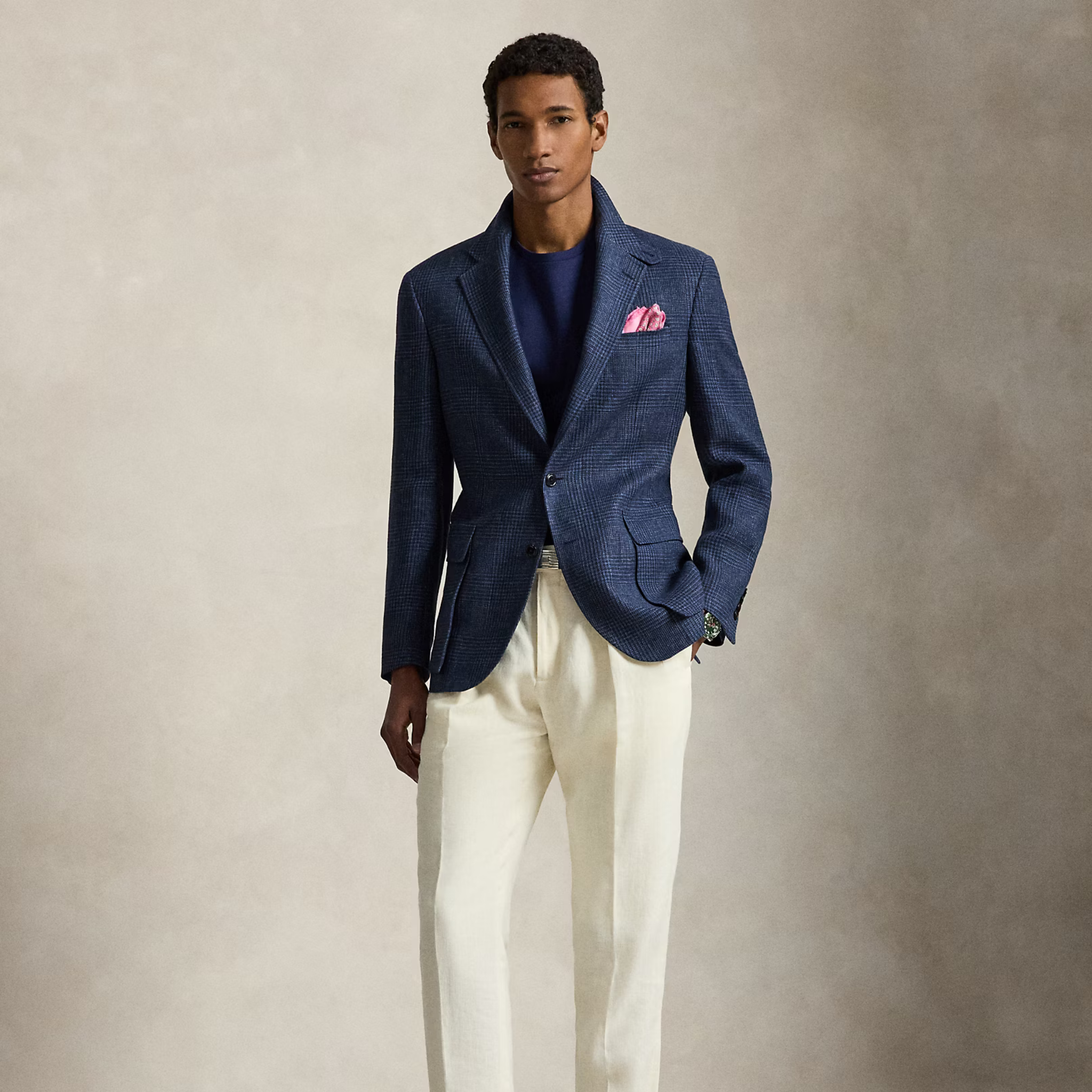 Man wearing a blue blazer and white pants against a neutral background