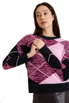 Long sleeved argyle crewneck sweater with mauve, pink, black, and white argyle print and black color blocked trim-sassanova